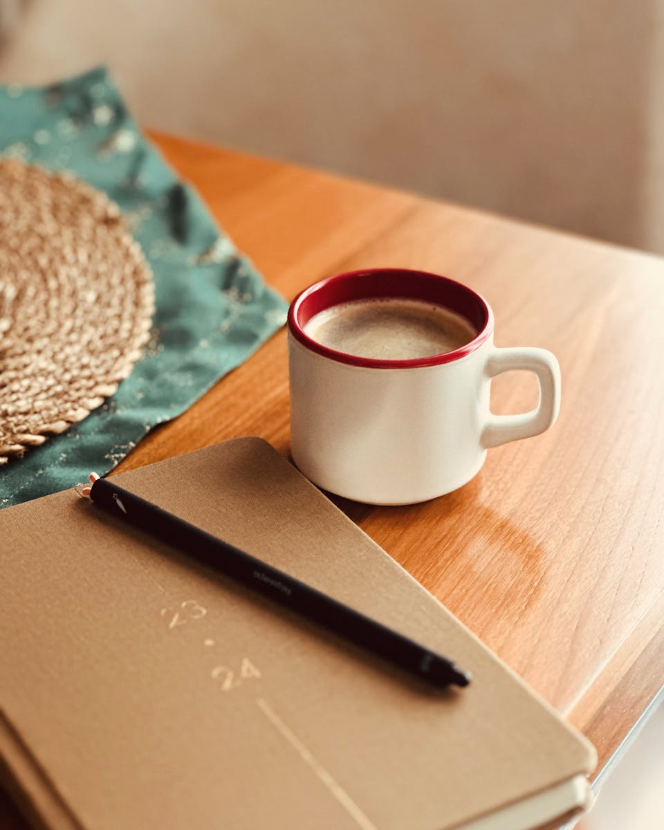 Illustrasjonsbilde av kaffekopp, notatbok og penn &ndash; rolig arbeidssituasjon hos psykolog